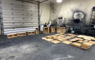 APEX Coating and Painting Services workshop with wooden cabinet components and spray painting preparation area
