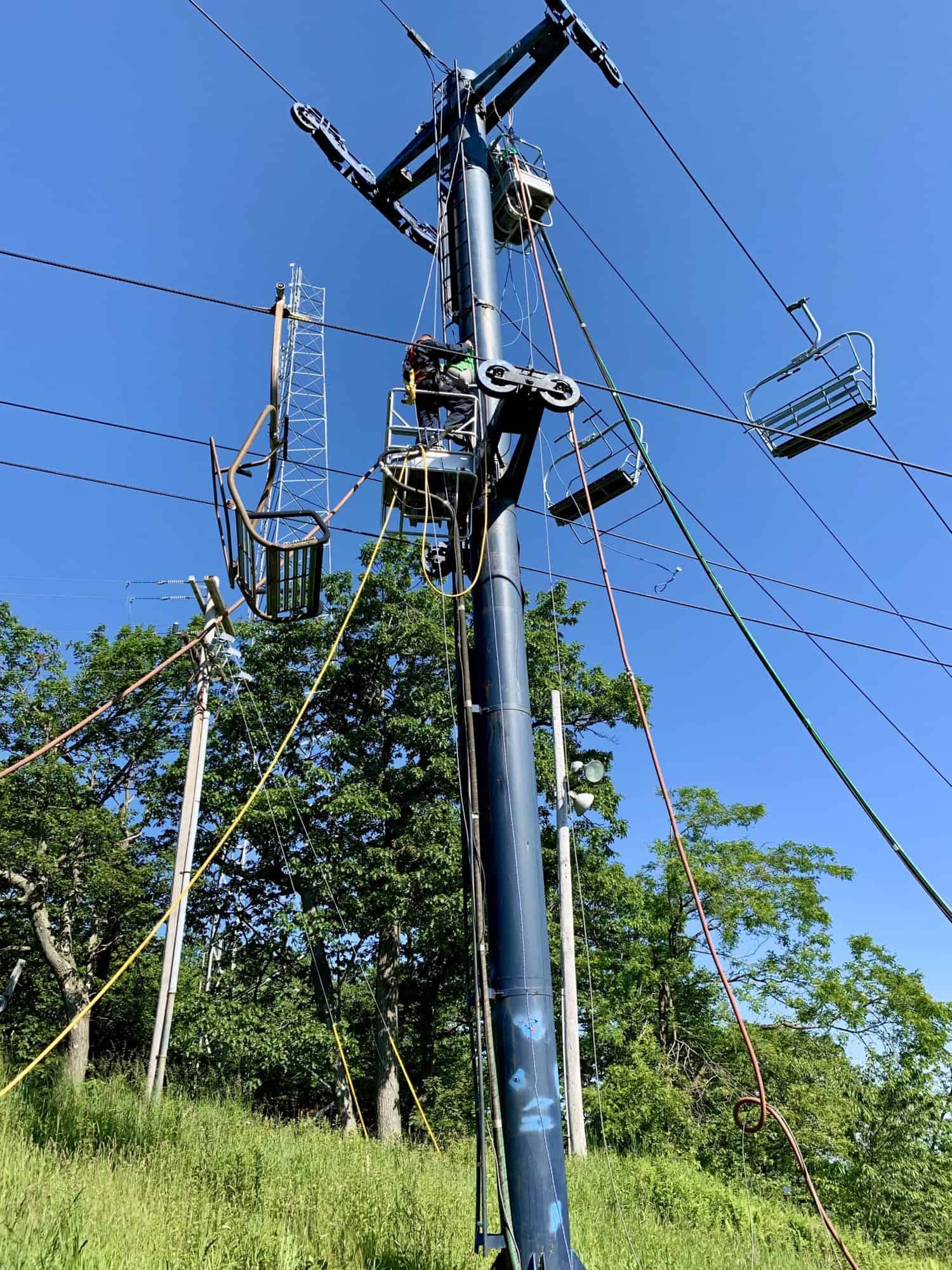 Ski lift tower with grey-blue paint, maintained by APEX Coating and Painting Services in wooded area
