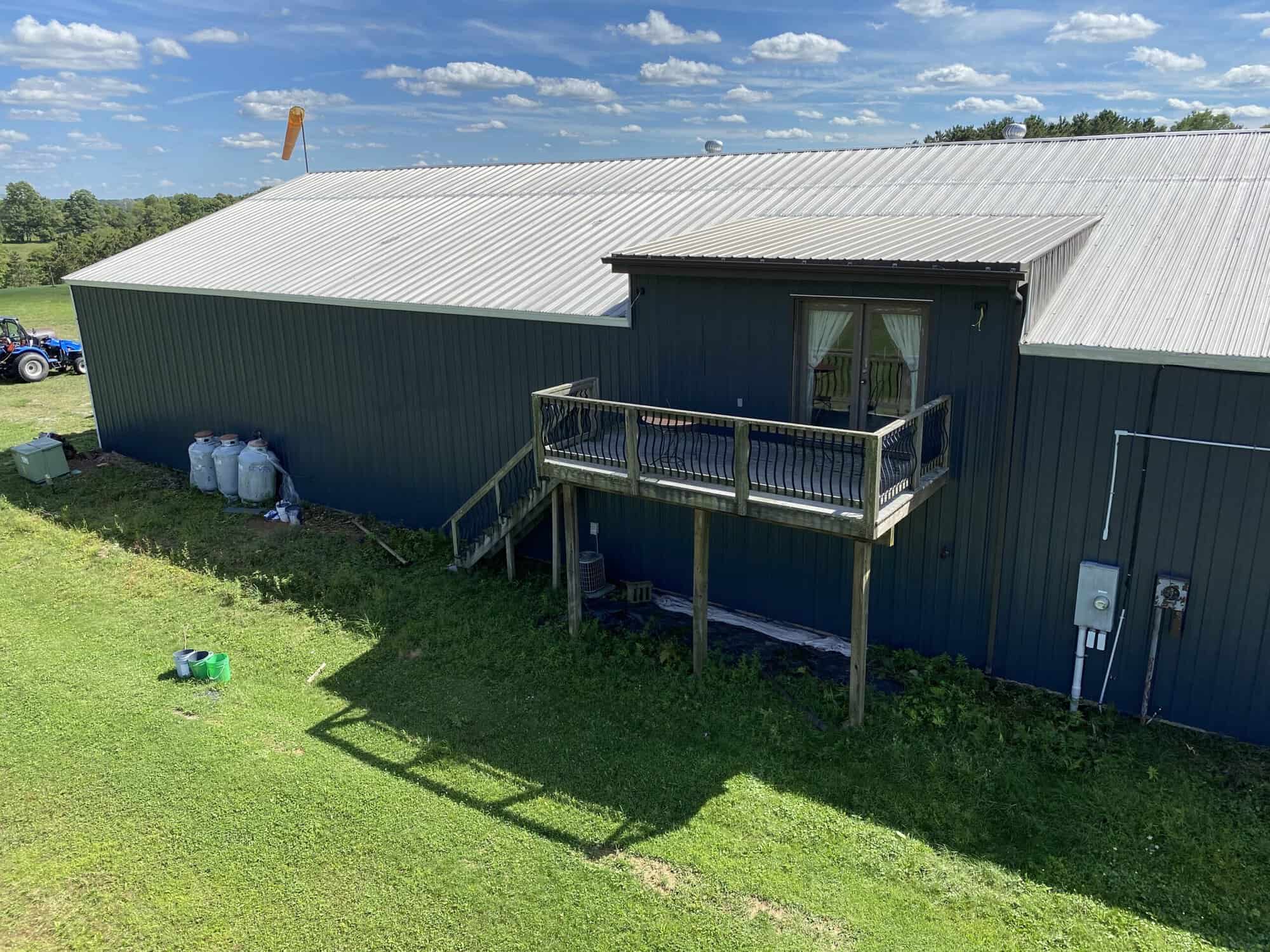 Large barn or agricultural building painted by APEX Coating and Painting Services, with two-story deck and white metal roof